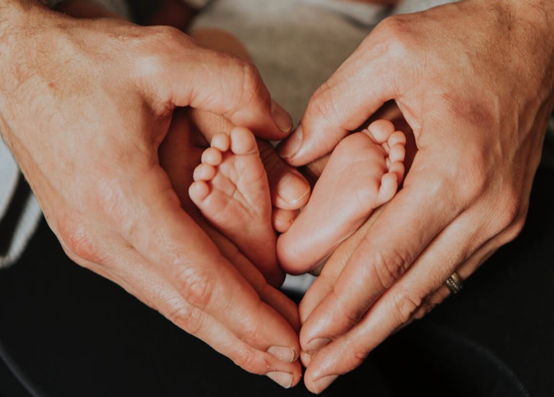 Parents gently holding their baby’s feet